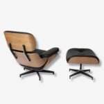 Side view of the Charles Eames Lounge Chair and Ottoman set, featuring an ash wood frame and black leather upholstery.